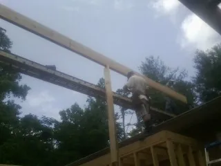 Carpenter setting a ridge beam over a new addition frame — Ice Dam Removal by Roofing Brothers in Fall Creek