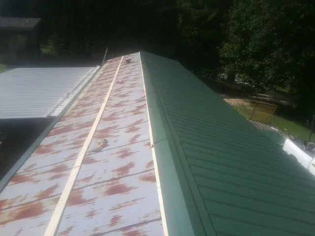 Old rusted panels beside newly installed green metal roofing — Wind Damage Roof Repair by Roofing Brothers in Fall Creek