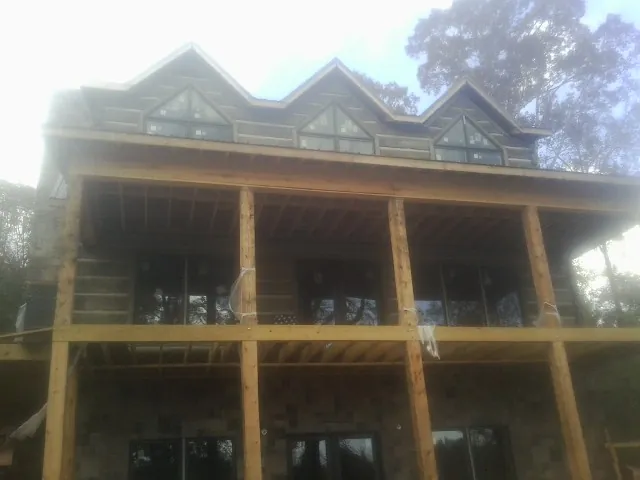 Dormers and porch framing on a large log home under construction — Roof Coating work by our crew in Fall Creek